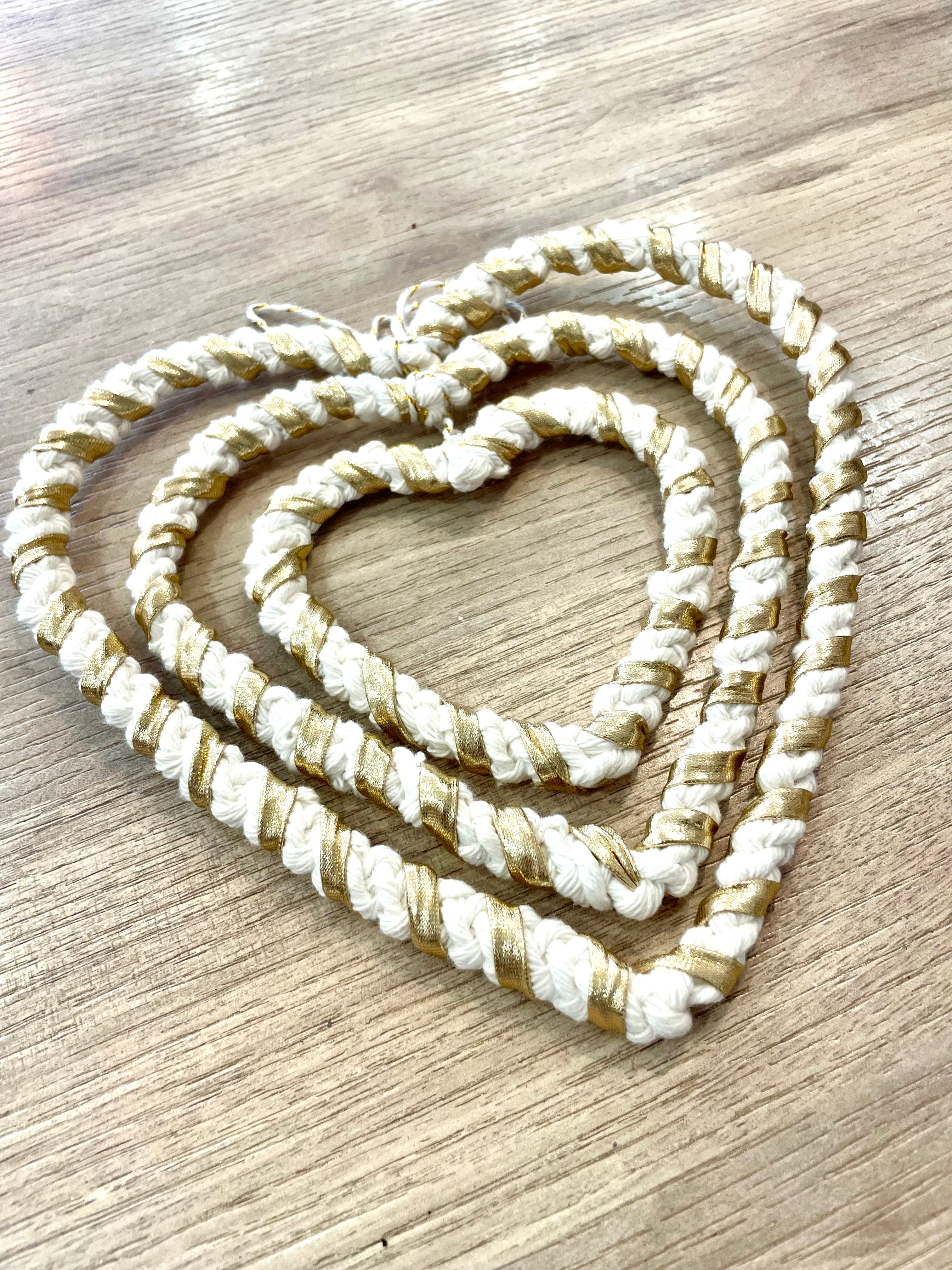 trois décorations à accrocher en forme de coeurs imbriquées les unes dans les autres couleur blanc et or nouées avec la technique macramé