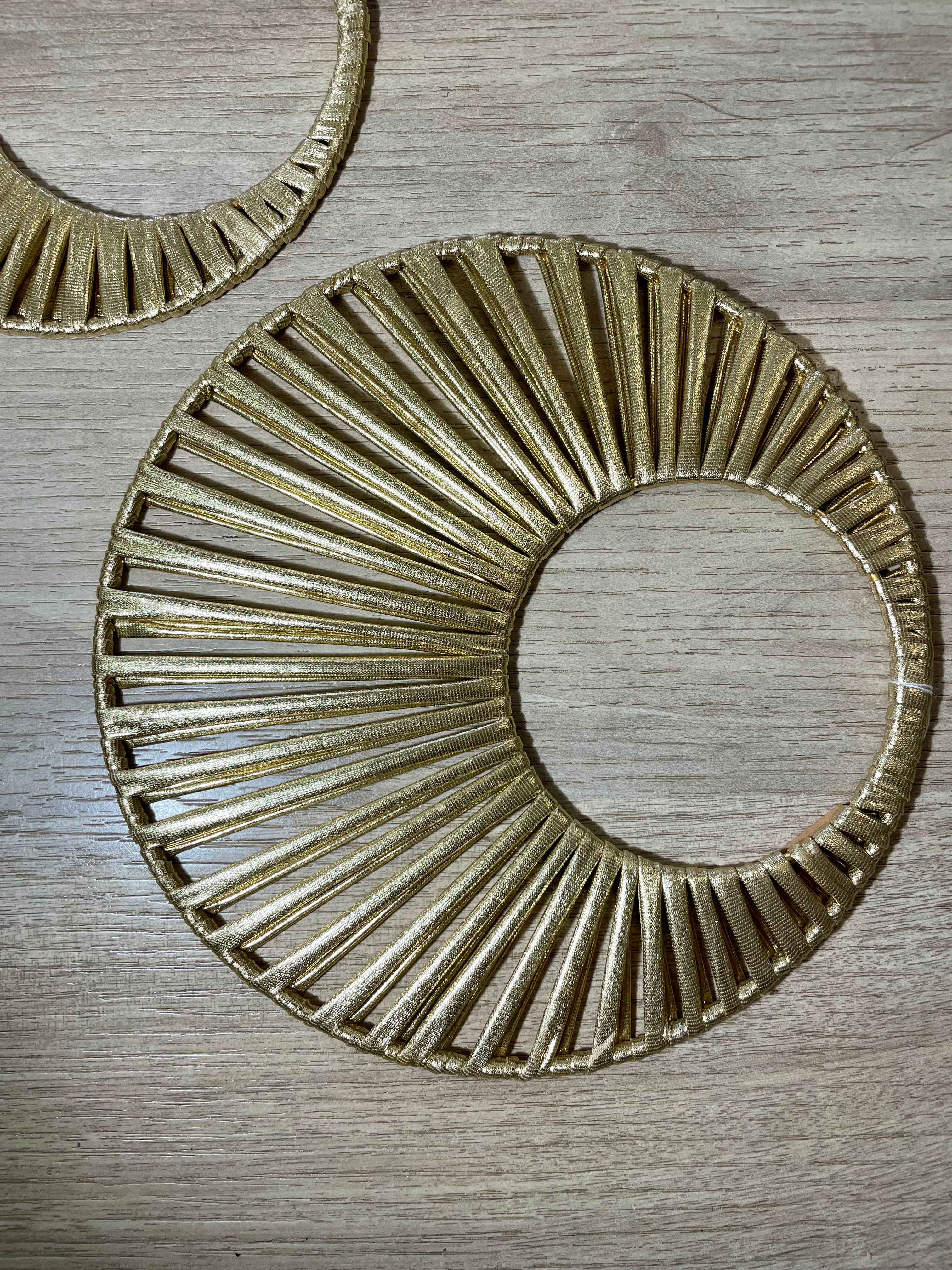 décoration dorée en forme de soleil deux cercles reliés par du tissu or formant un beau soleil