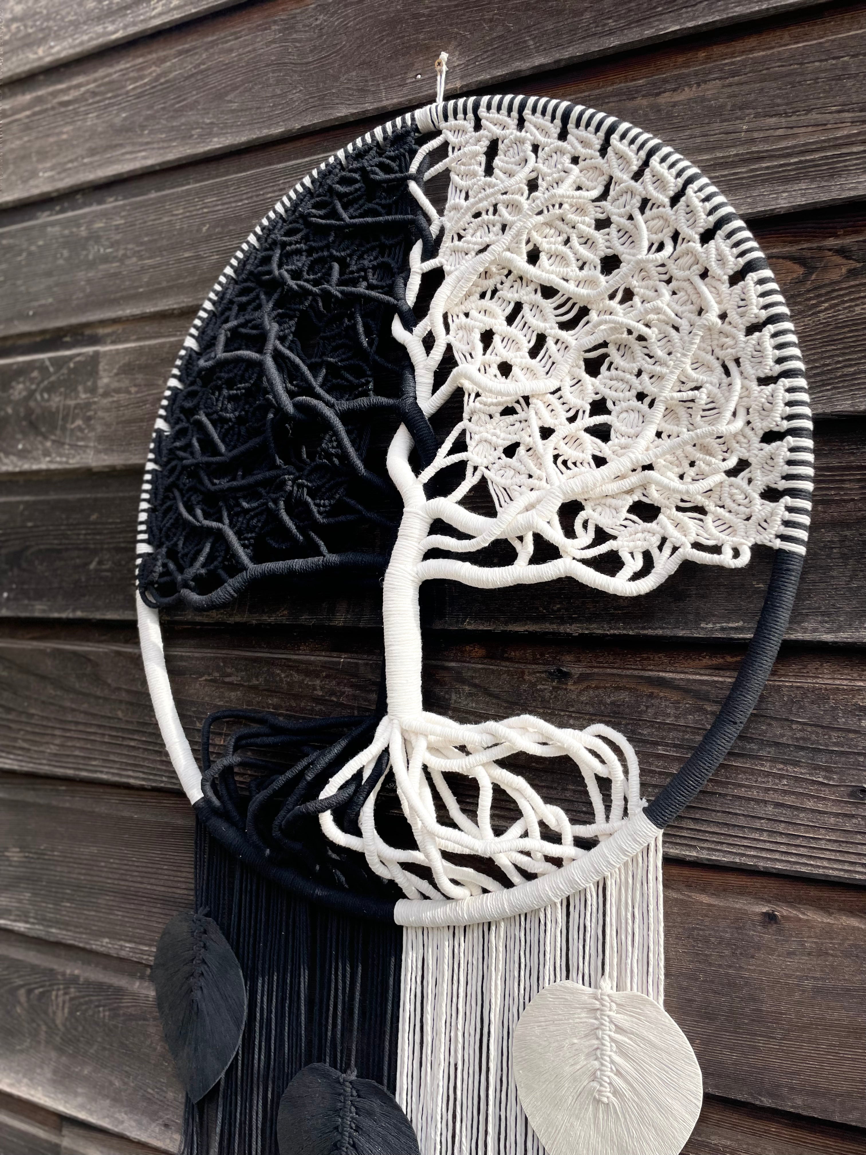 belle création artisanale en macramé avec de la corde de coton un coté noir un coté blanc réalisé autour d'un cercle de 80 cm de diamètre montrant les détail des feuilles des branches du tronc et des racines