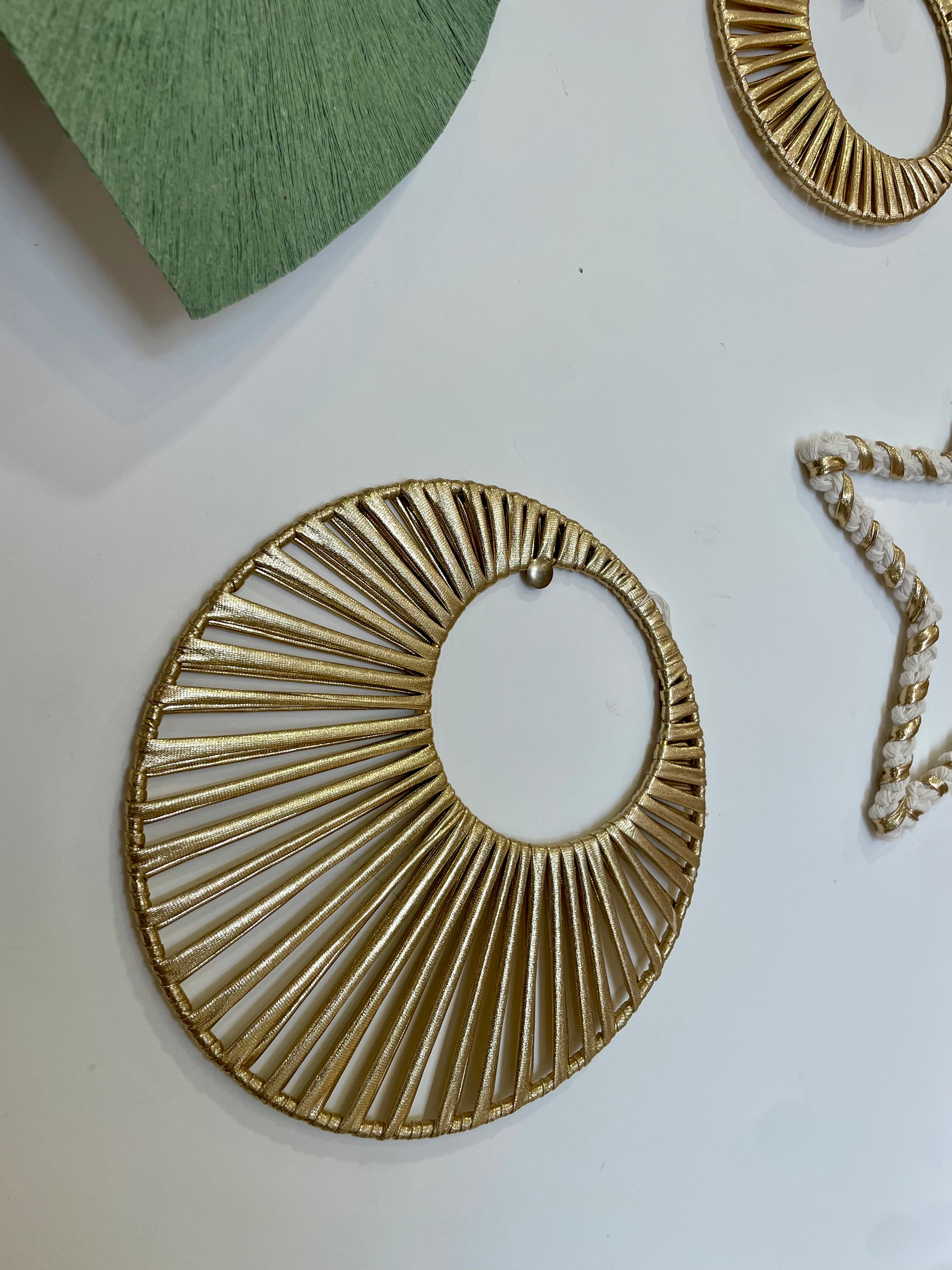 décoration soleil doré accroché sur un mur à coté d'une étoile en macramé beaucoup de brillance et de lumière