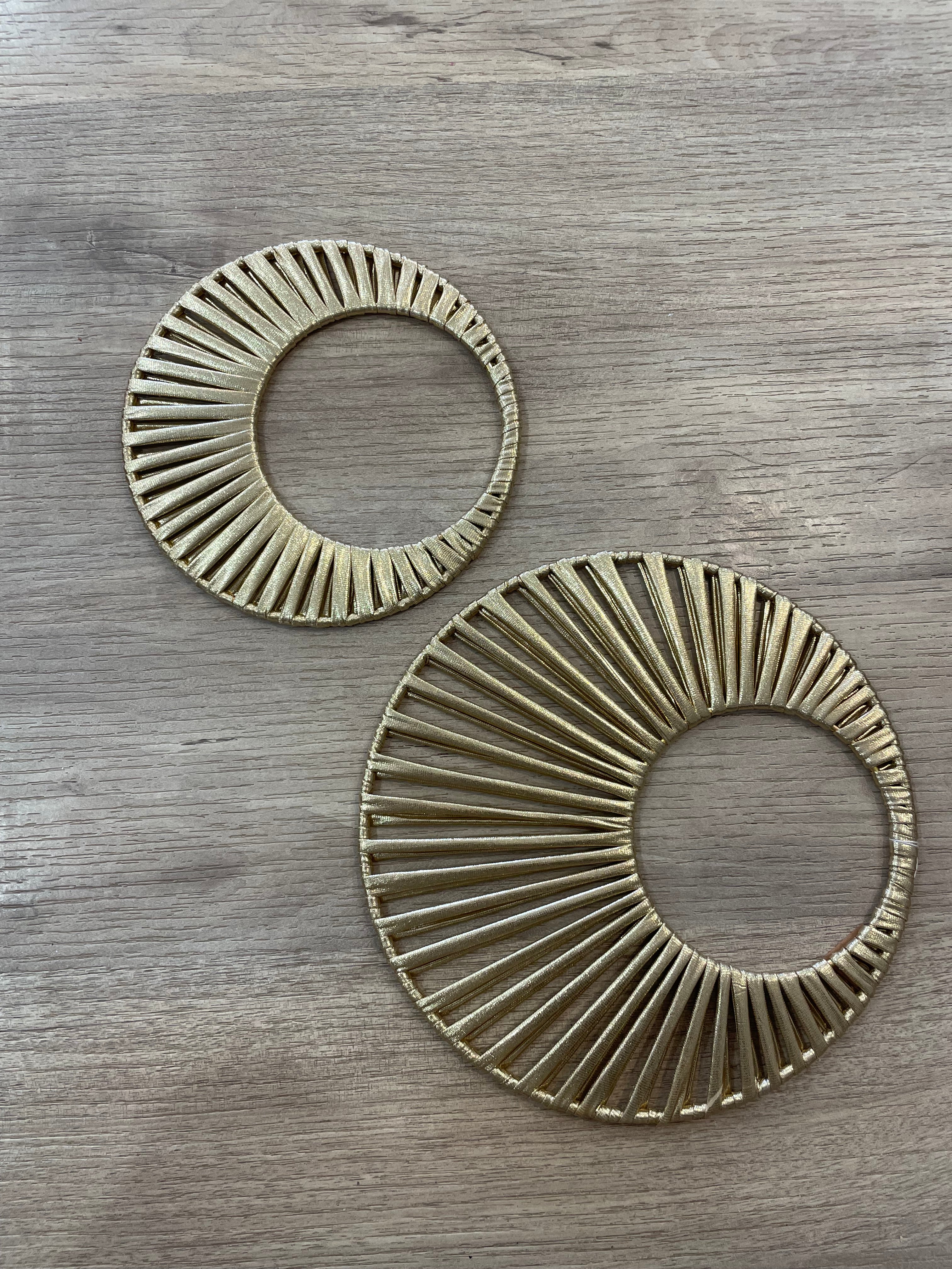 deux décorations en forme de soleil fabriquées à la main avec du tissu doré laissant quelques jours entre les rayons 