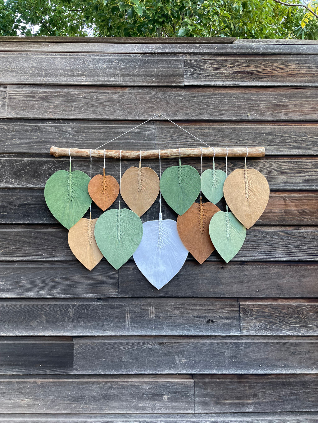 décoration murale vue d'ensemble technique macramé pour un rendu naturelle dans les ton vert marron beige blanc feuilles suspendues sur un bois flotté