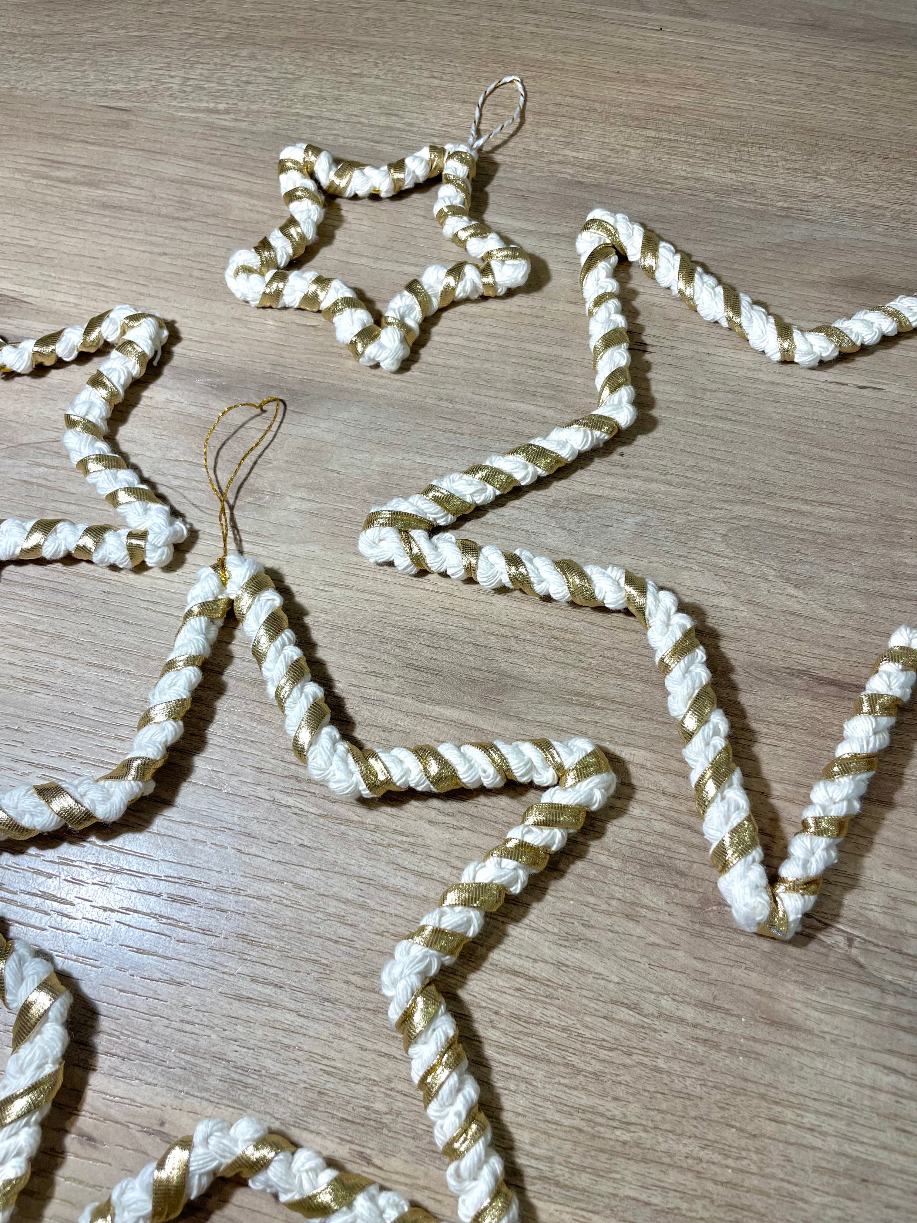 zoom sur des décorations en macramé en forme d'étoiles de tailles différentes couleur blanc et or à accrocher par un fil doré