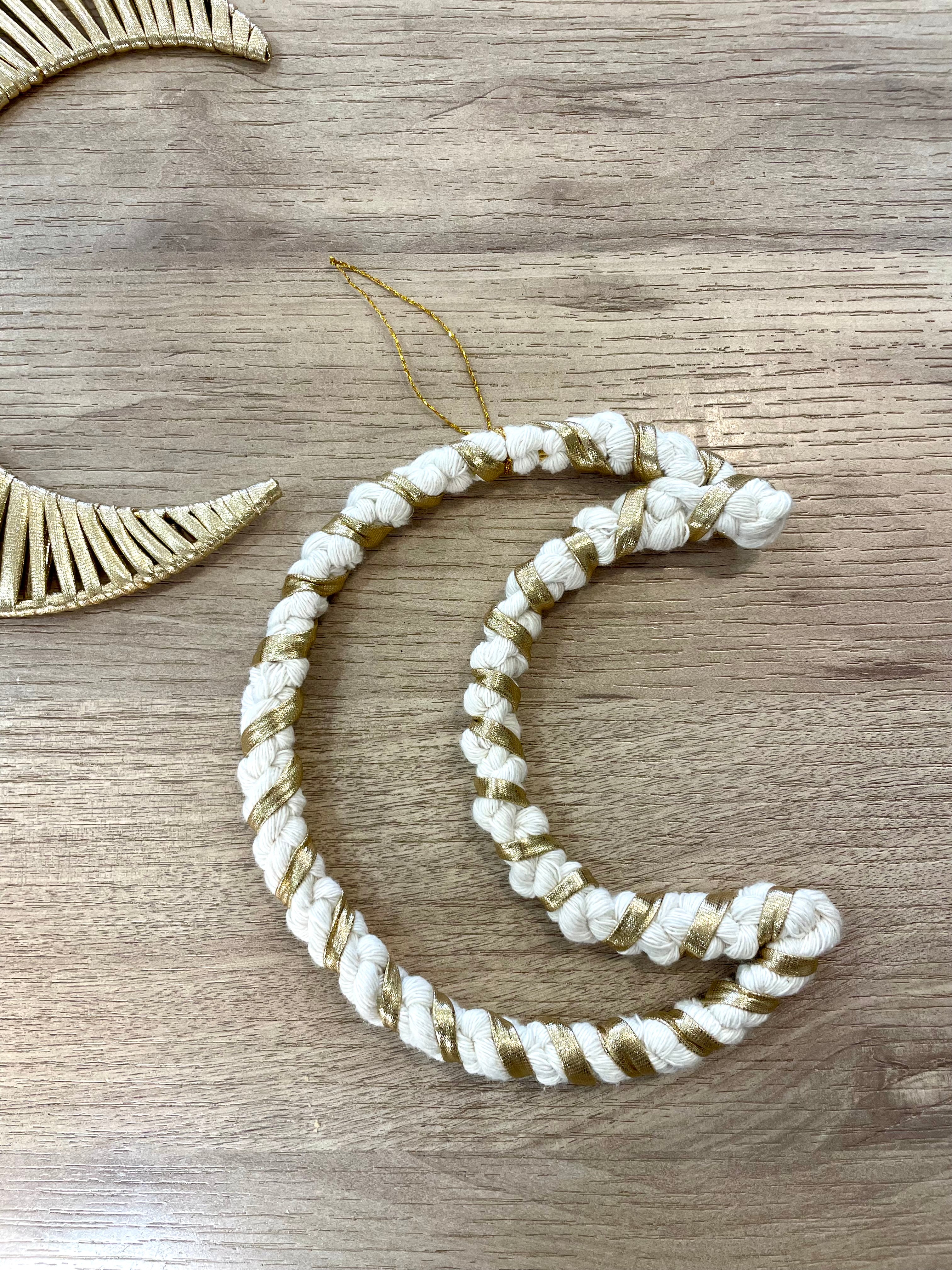 décoration artisanale technique macramé réalisée avec du fil de coton blanc et du tissu doré à suspendre avec un fil doré