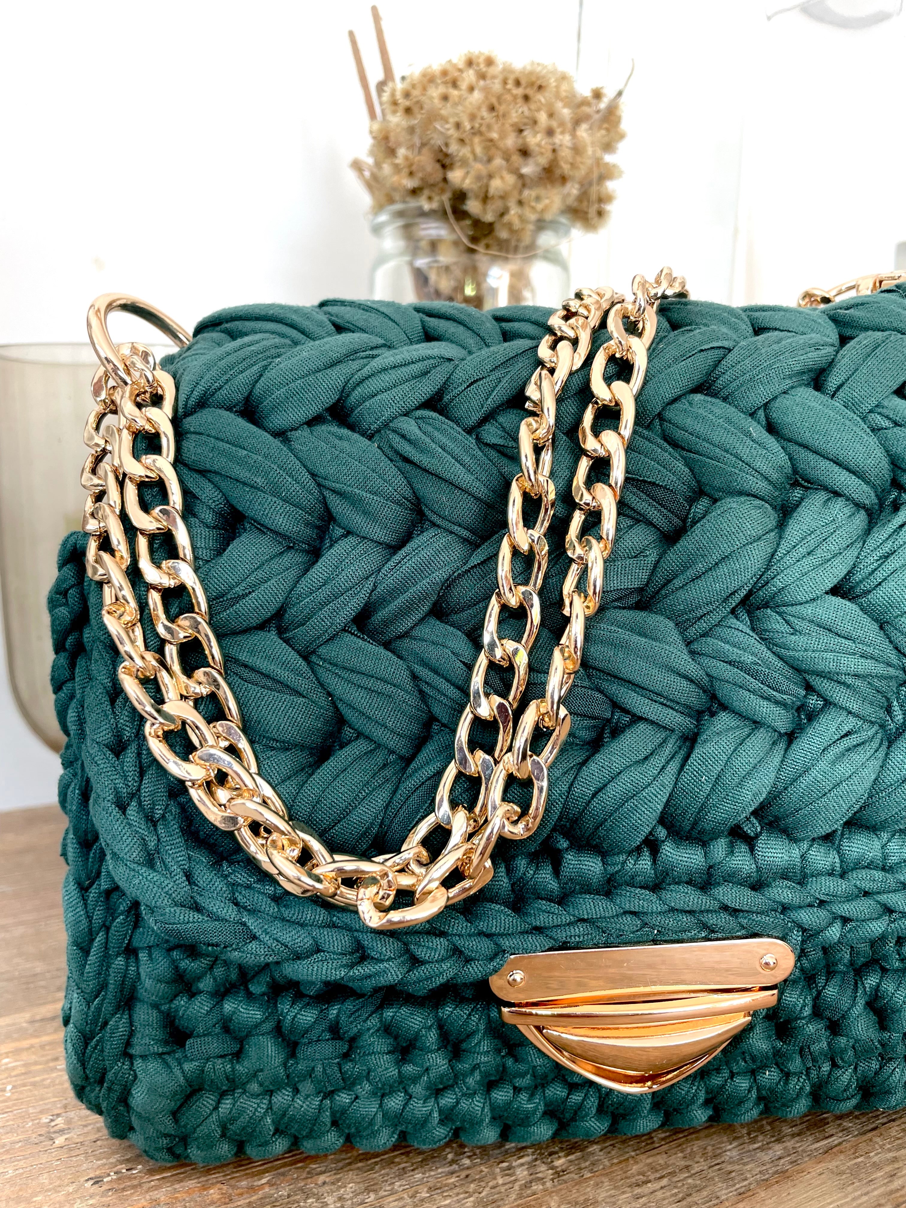 zoom sur un sac vert au crochet avec une sangle et un fermoir en métal doré