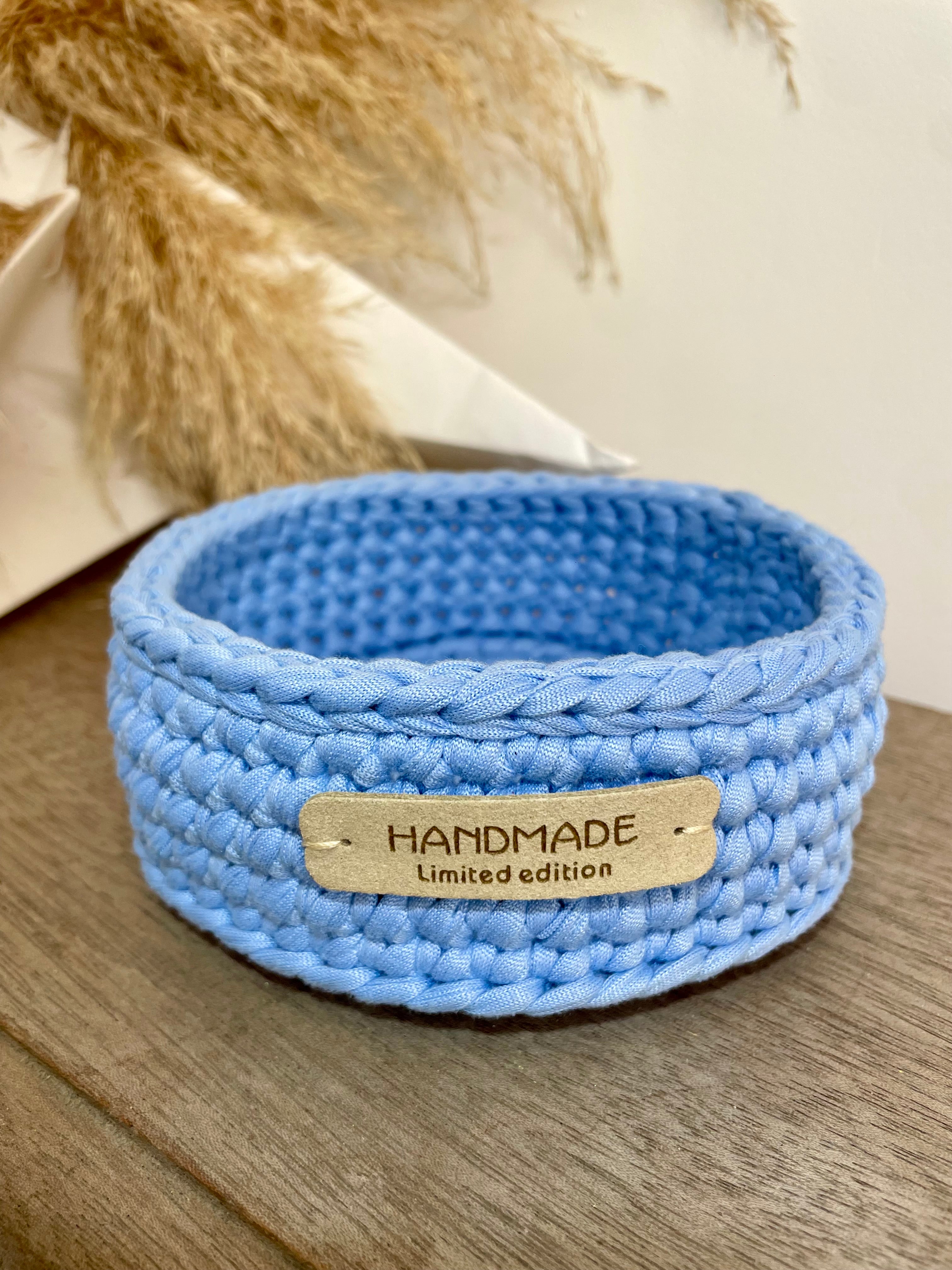 panière bleue claire au crochet avec étiquette en cuir beige handmade limited edition, posée sur du bois