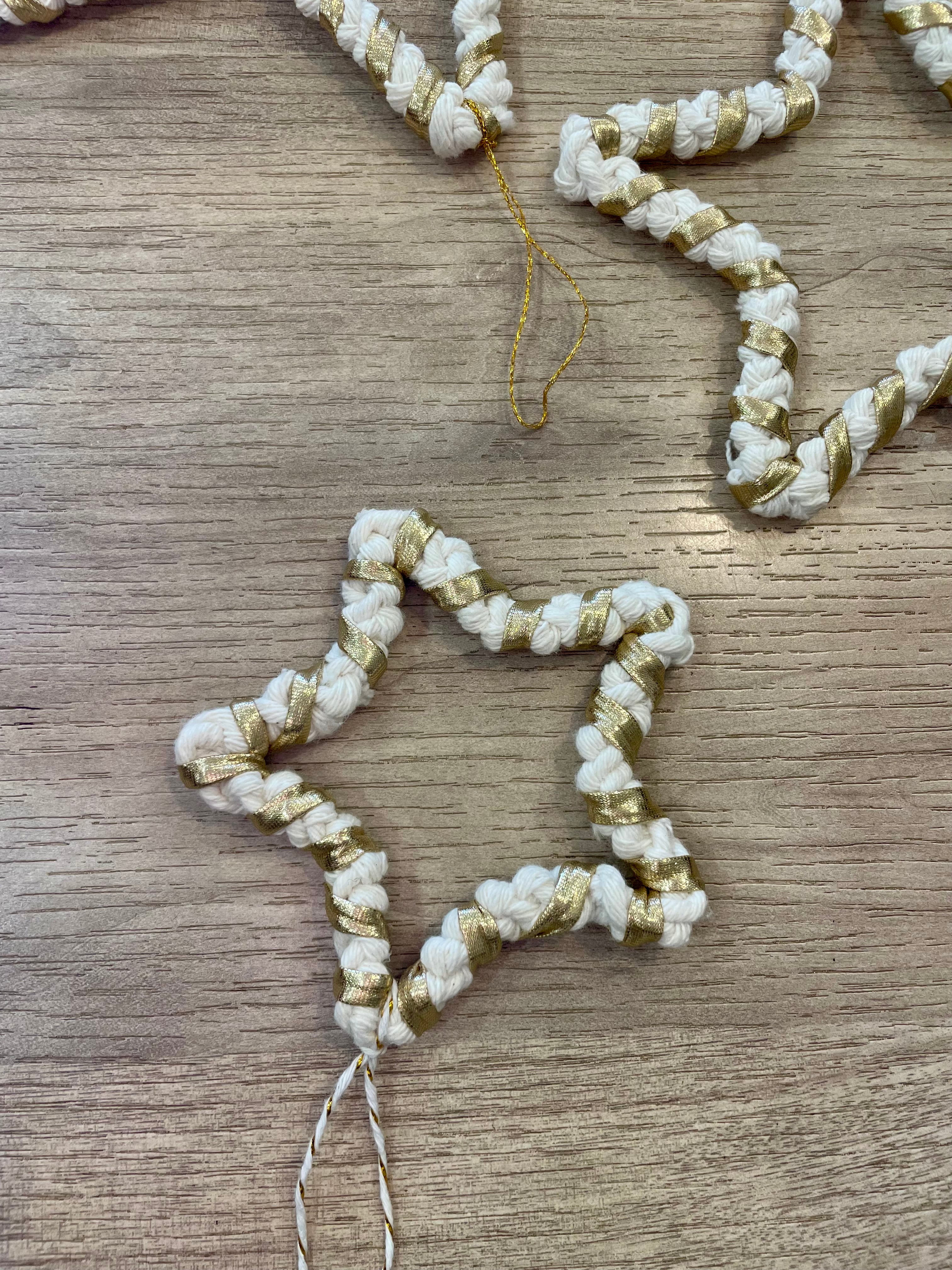 décoration en forme d'étoile de petite taille tressée avec la technique du macramé de couleur blanc et doré