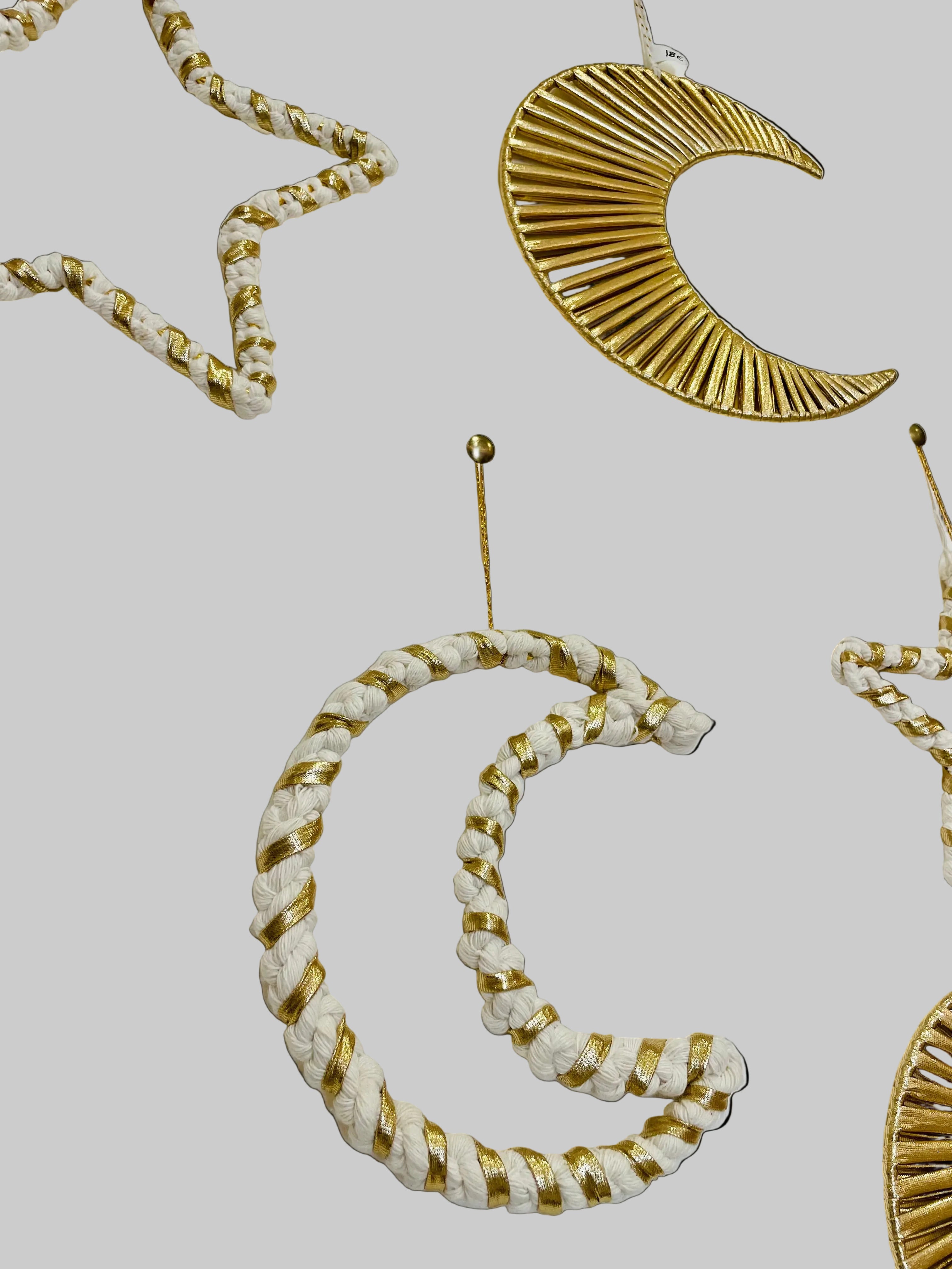 plusieurs décorations accrochées au mur les unes à coté des autres lune et étoile en macramé suspendues par un fil doré