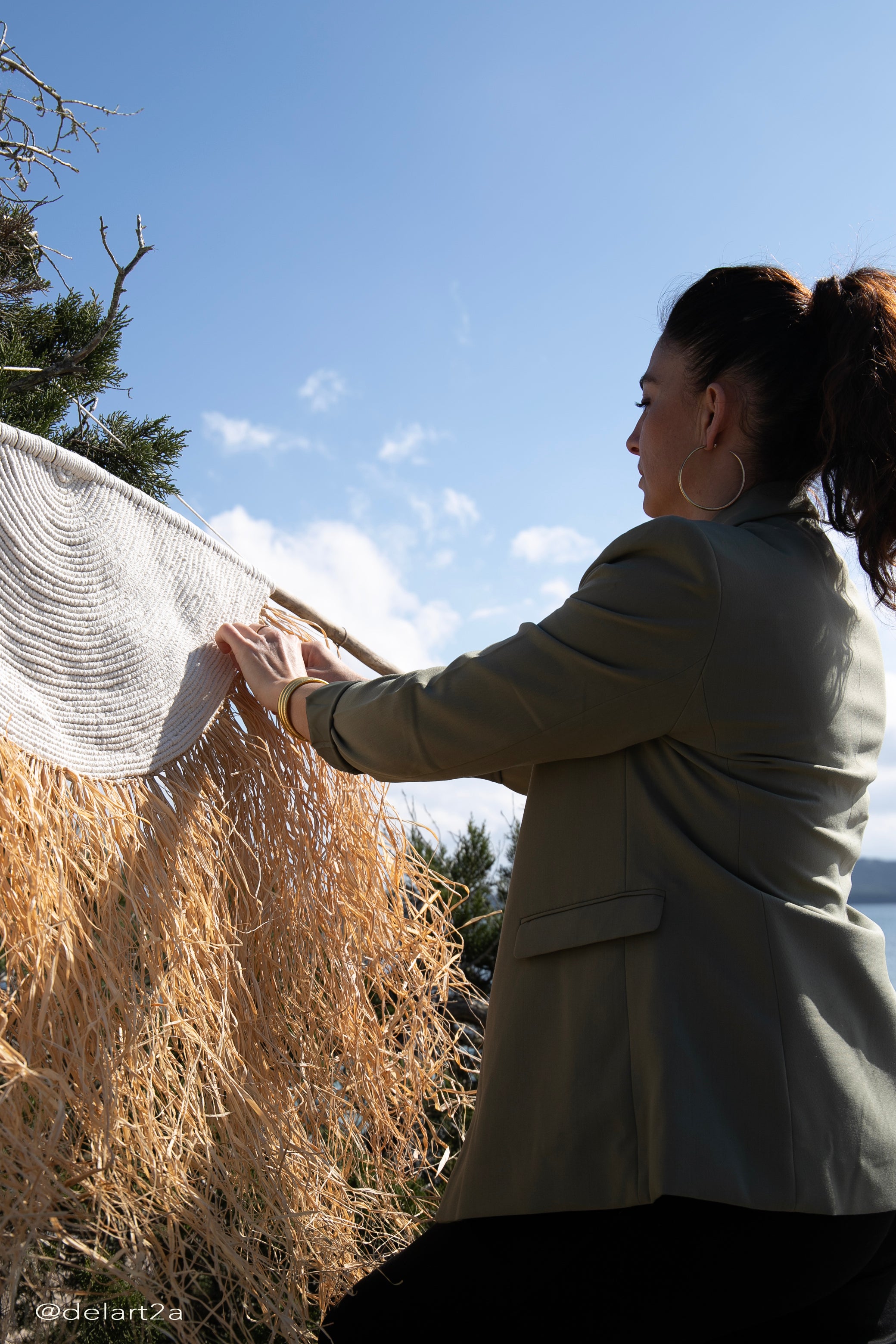 photo de la créatrice ava isula atelier travaillant à la plage sur une création en raphia corde de coton blanc et raphia