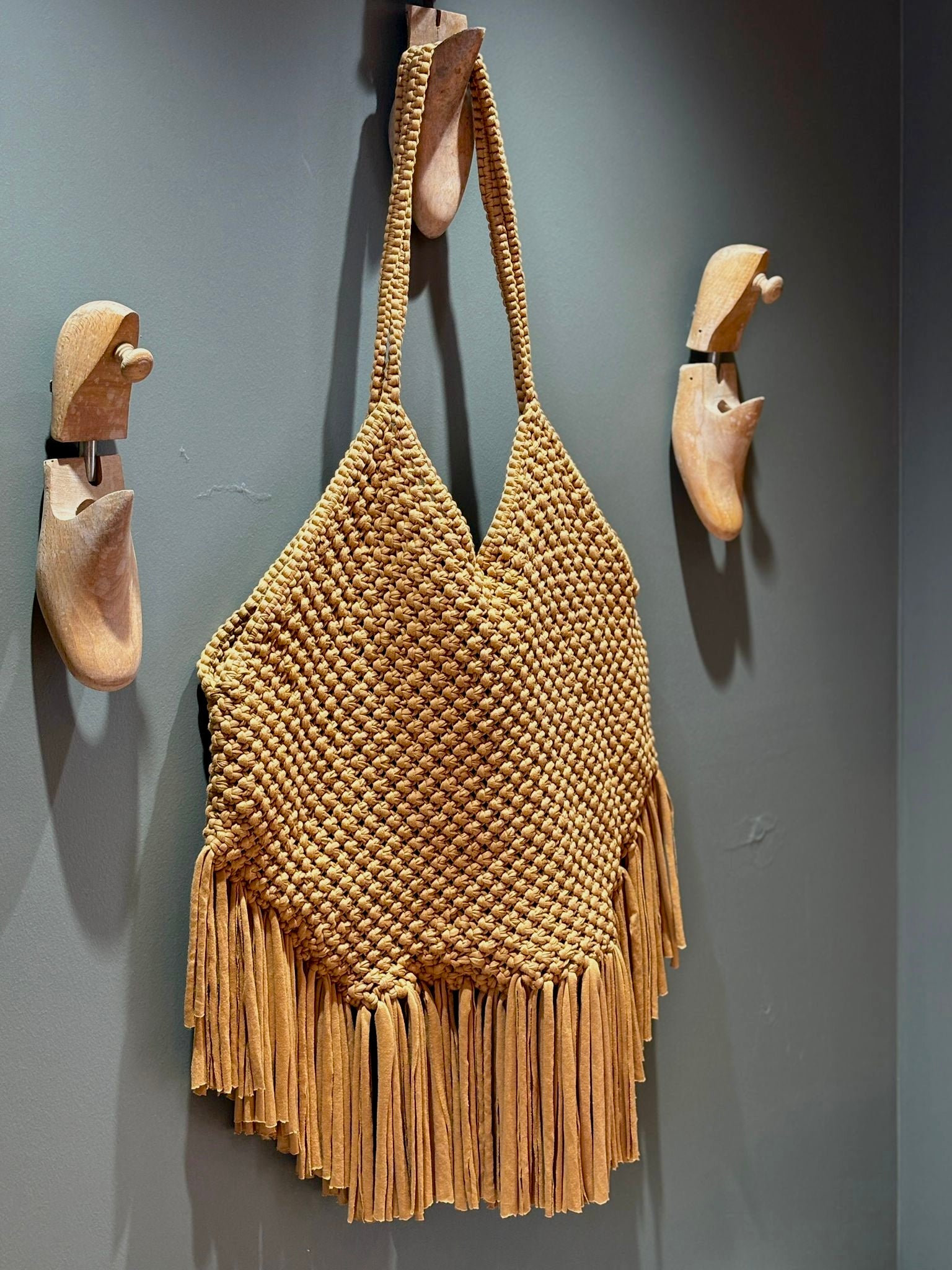 sac à franges couleur caramel beige marron technique de nouage en macramé porté épaule accroché contre un mur sur une patère en forme de chaussure