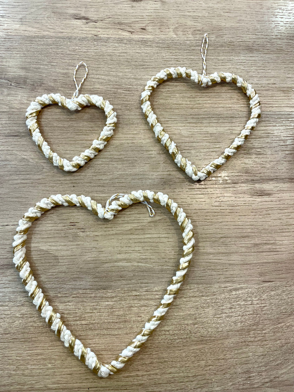 3 décorations à suspendre en forme de cœur de tailles différentes tressés avec la technique macramé de couleur blanc et doré 