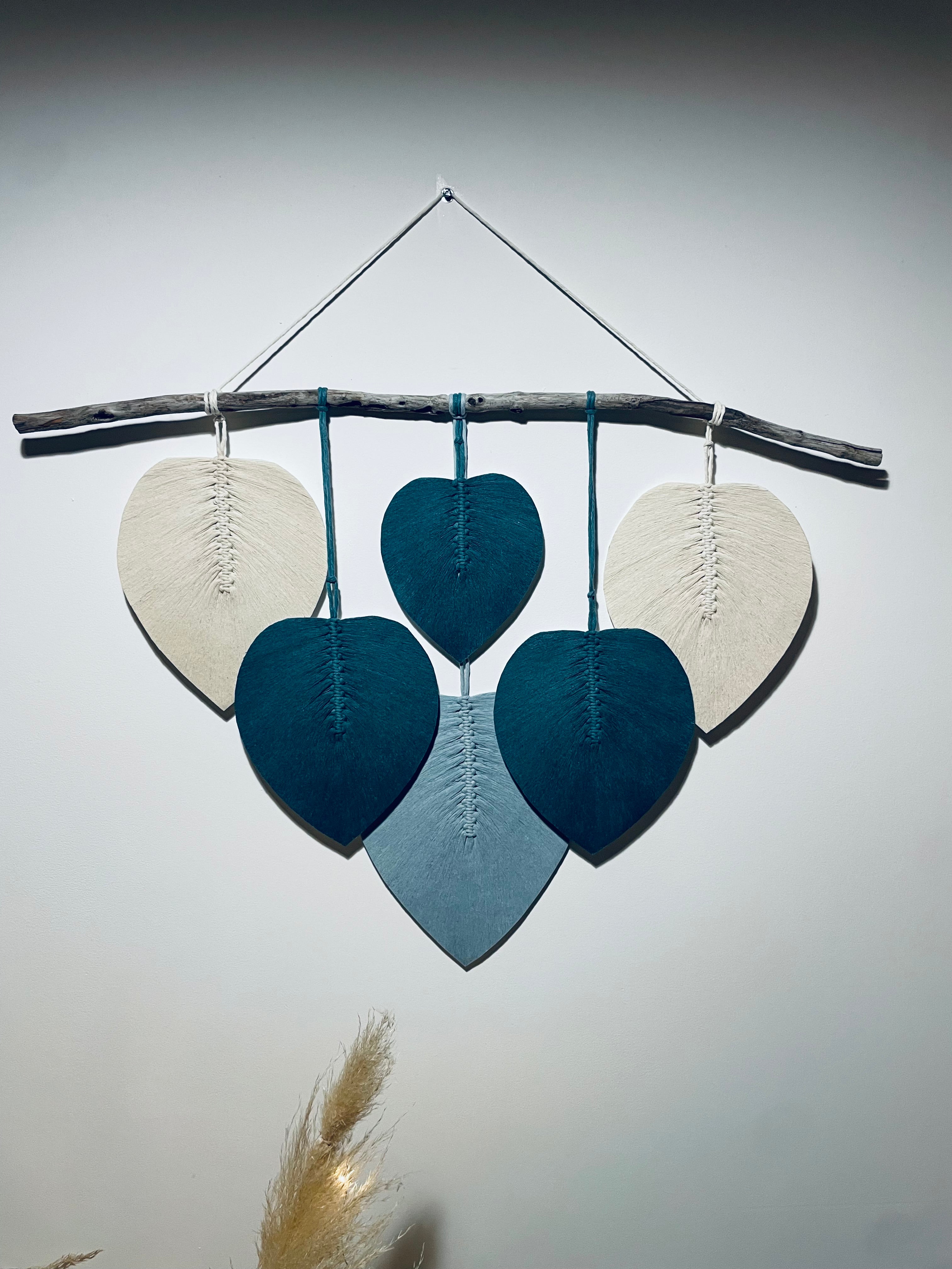 vue d'ensemble d'une décoration murale avec un bois flotté accroché a une ficelle sur lequel sont suspendues des feuilles en corde de coton bleu et blanc stabilisé