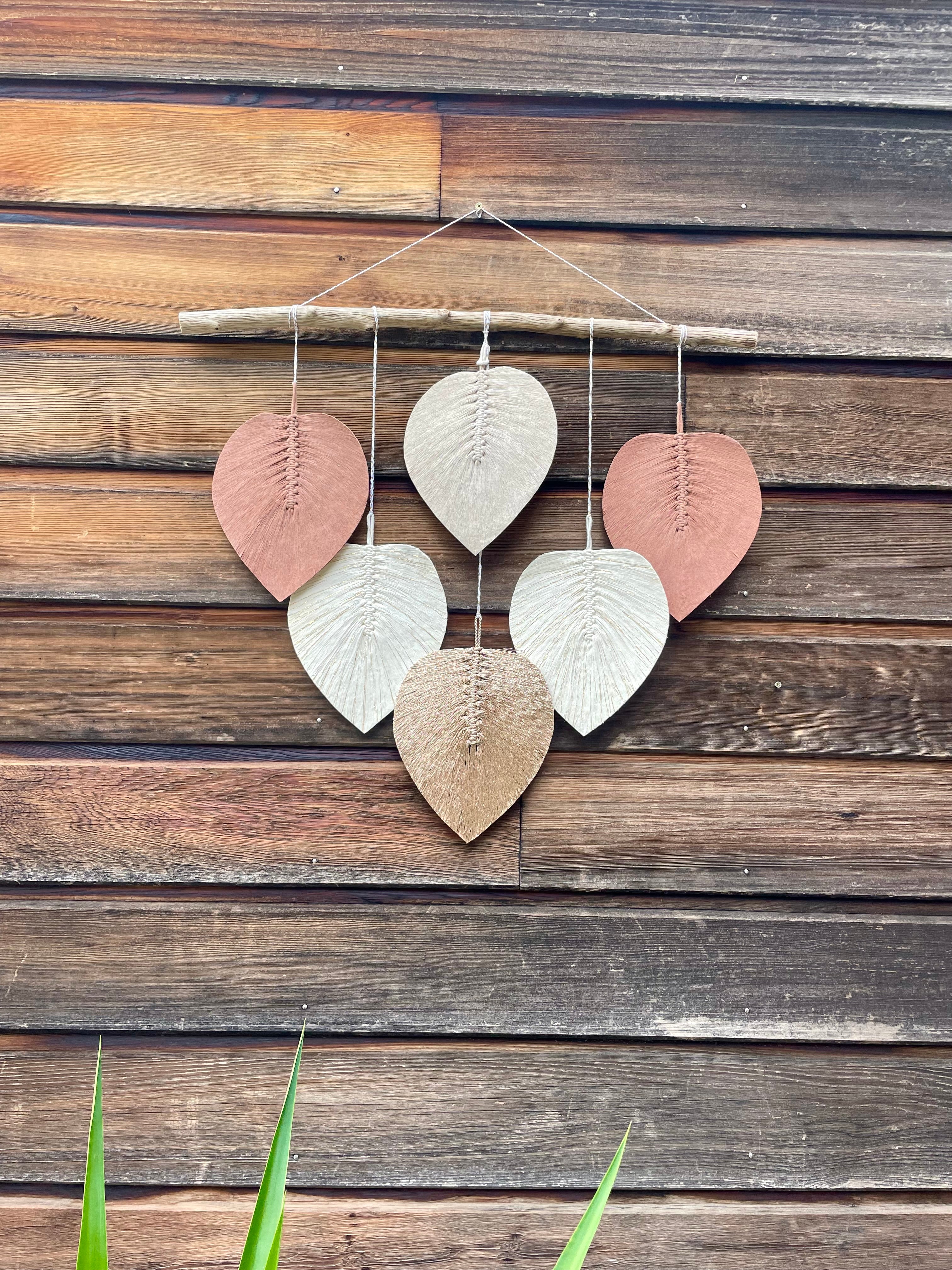 vue d'ensemble sur une décoration murale bois flotté sur lesquelles sont suspendues des feuilles en corde de coton stabilisé couleur or blanc doré beige et terracotta technique macramé
