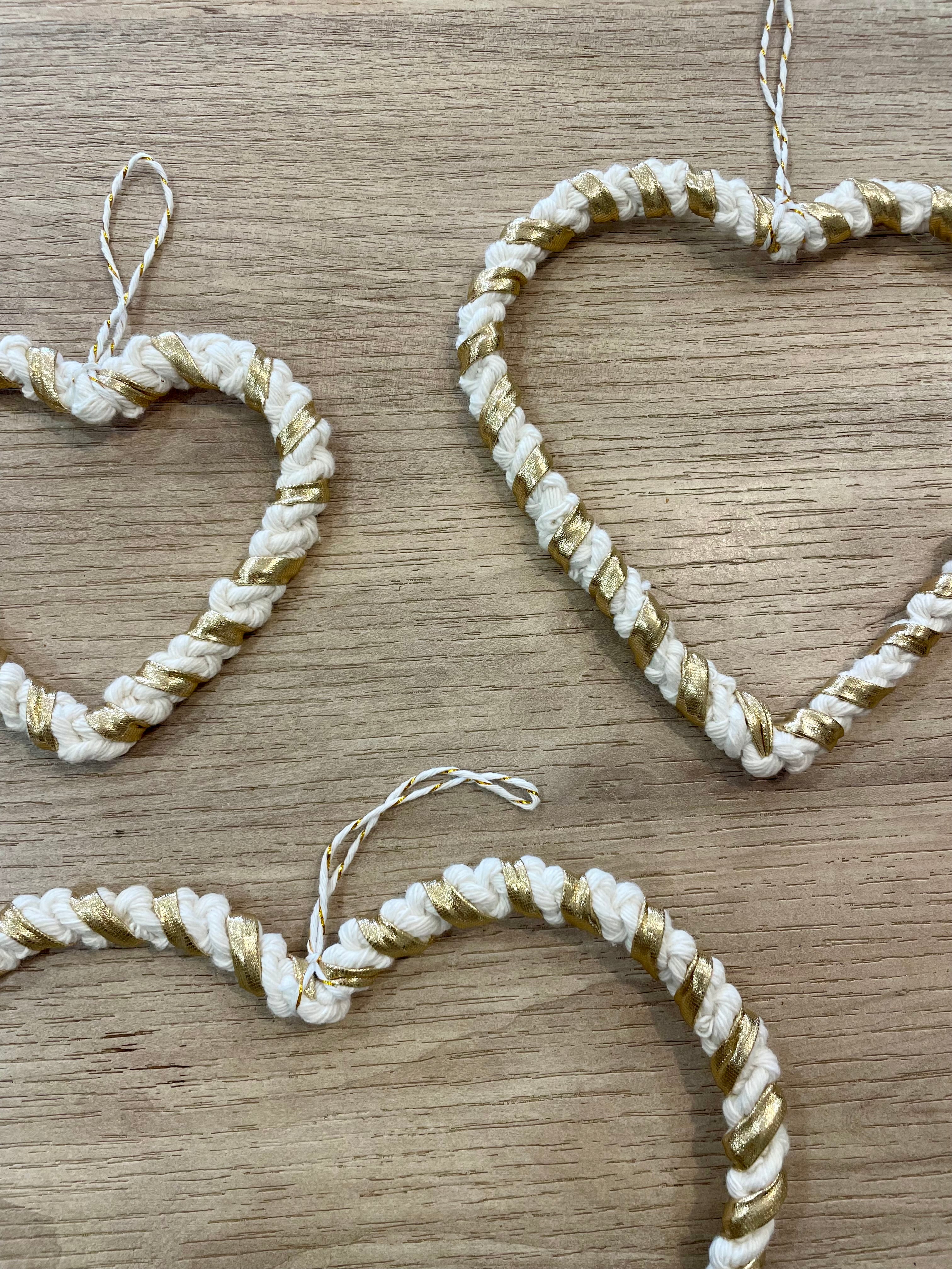 zoom sur 3 décorations de taille différentes à accrocher en forme de cœurs de couleur or et rème